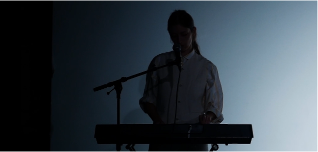 une silhouette derrière un clavier dans une ambiance de scène peu éclairée