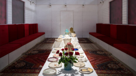 Photo de l'installation. Un grande table avec beaucoup de vaisselle, dans un salon traditionnel afghan.