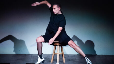 Portrait d'Israel. Il est assis sur un tabouret et ses bras dansent.