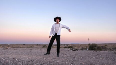 Photo de Grégoire Schaller dans un désert, au coucher de soleil. il est habillé comme un cowboy et il fait un pas de danse.